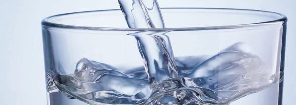 Wasser in ein Wasserglas gießen